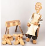 A carved wooden cobbler shop display model. Includes wooden bench and an assortment of wooden