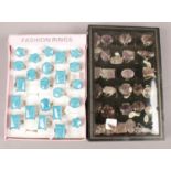 Two display cases of fashion dress rings set with hardstones.