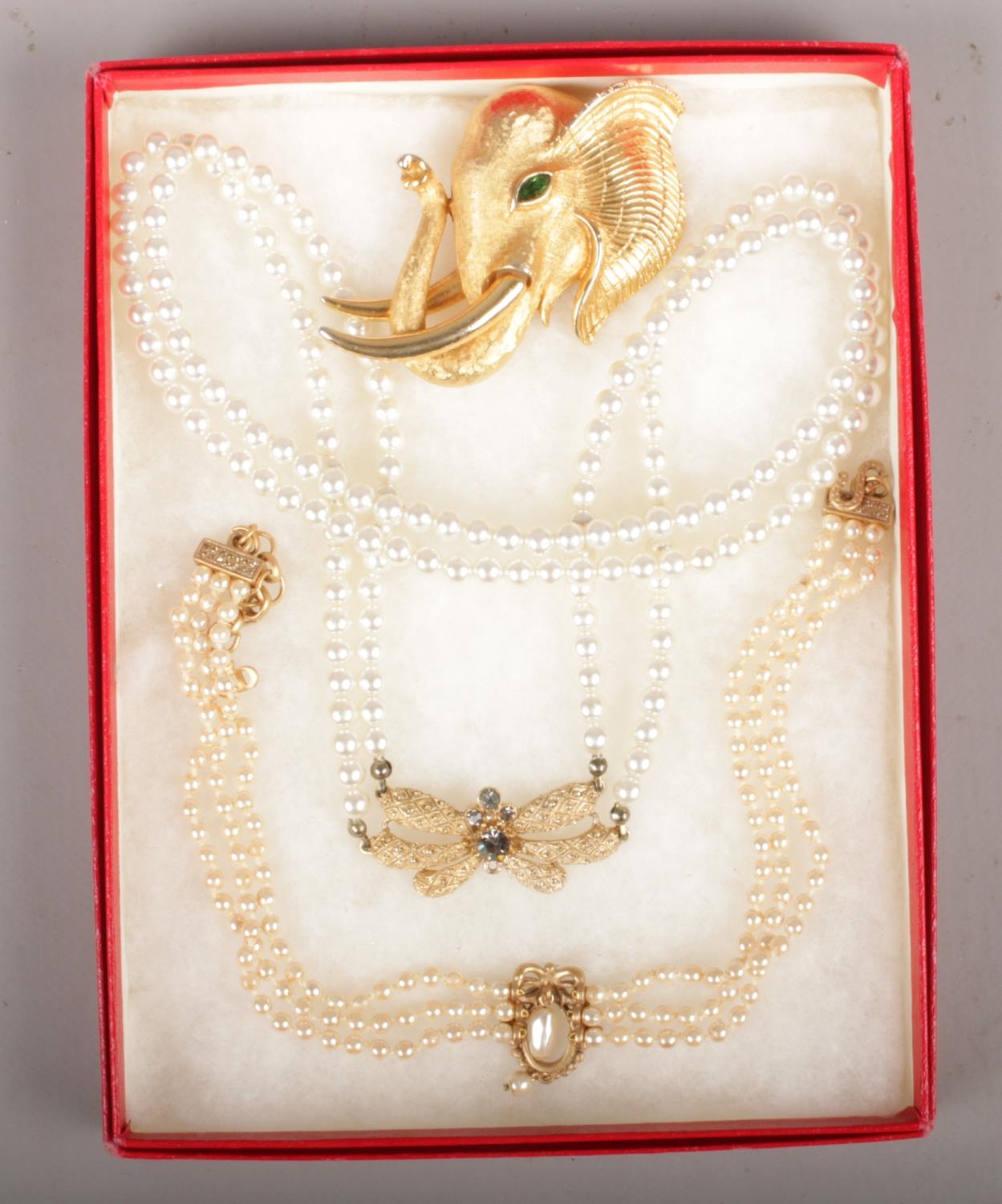 A Christian Dior faux pearl costume necklace along with a similar example and a gilt elephant