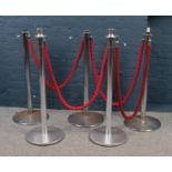 Two sets of Weighted chrome stanchion poles with red twisted barrier ropes.