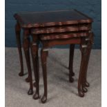 A nest of tables (3) in carved mahogany with glass tops. 56cm height 54cm width 37cm depth.