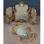 An ornate gilt framed triple fold mirror along with a similar wall mirror.