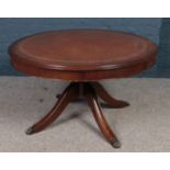 A circular centre pedestal leather inset coffee table with paw feet.