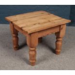 A square pine coffee table with turned supports.