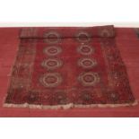A vintage Bokhara red ground wool rug. Length: 195cm, W: 126cm. Condition fair. Rug is worn in