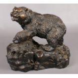 A large cast bronze sculpture of a bear on a rock, stamped P J Mene. (37cm x 40cm)