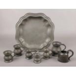 A Liberty & Co Tudric pewter dish, along with a collection of pewter measures and a jug.
