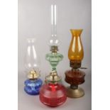 Four coloured glass oil lamps.