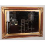 An ornate wood effect and parcel gilt frame bevel edge wall mirror. 71cm x 96cm.