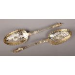 A pair of Victorian silver gilt berry spoons. With figural terminals and embossed decoration.