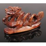 A Japanese box wood Netsuke style signed carving of a Dragon. H: 4.5cm, W: 7cm.