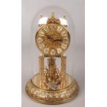 An ornate brass Kieninger & Obergfell torsion clock under glass dome.