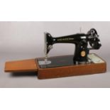 A portable 'Singer' sewing machine. Model no EF534272. Mounted on wooden base with drop down