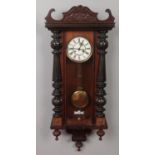 A carved mahogany wall clock. With roman numeral markers.