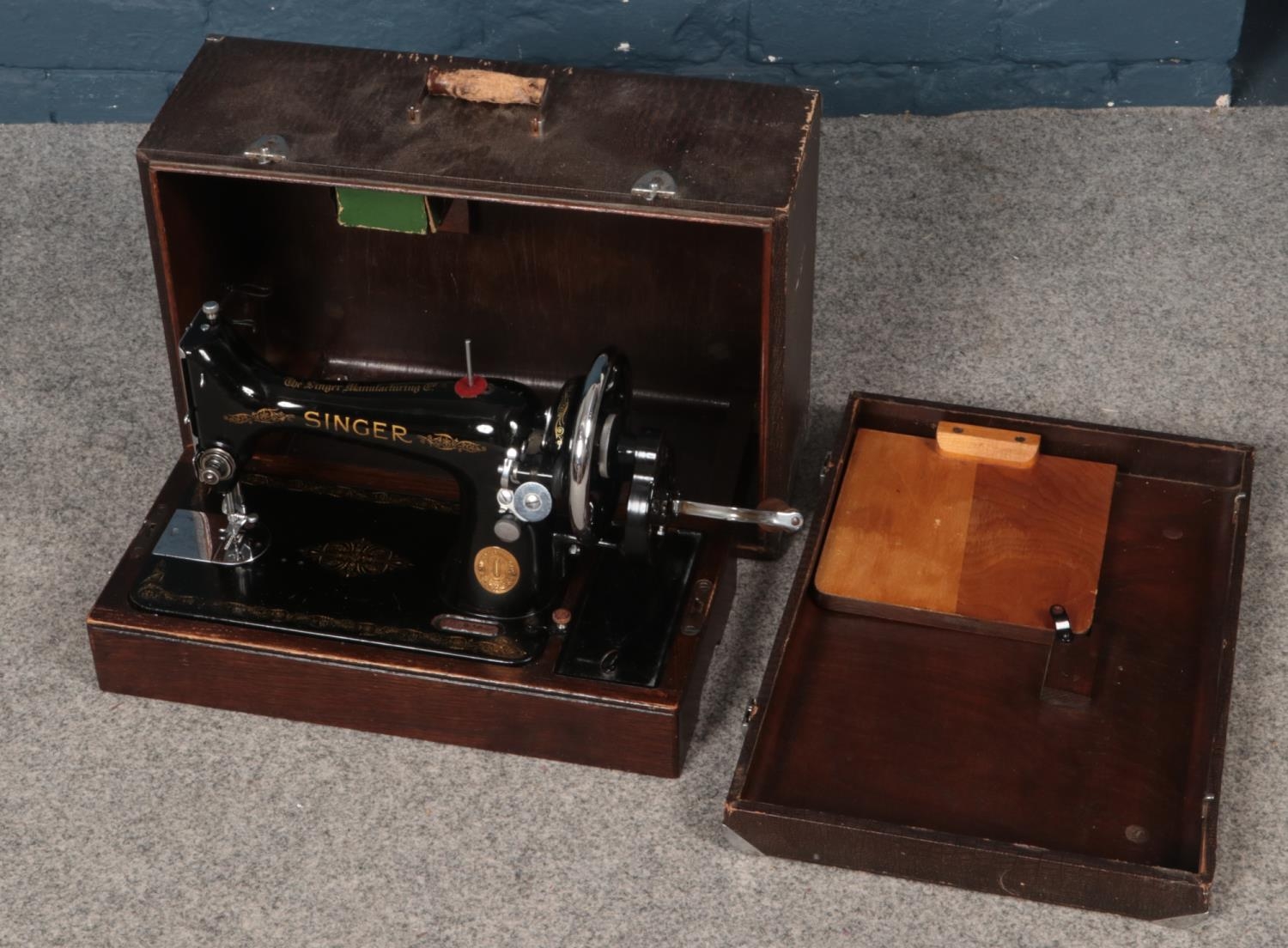 A cased Singer hand crank sewing machine.