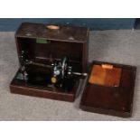 A cased Singer hand crank sewing machine.