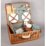 A wicker picnic basket and contents. To include plates, condiment set & four wine glasses etc.