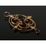 A yellow metal openwork pendant set with amethyst coloured stones and seed pearls.