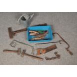 A box of tools. Including hammers, saws, water can, etc.