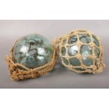 Two vintage hand-blown glass fishing floats with nets. Condition fair. One of the nets needs some