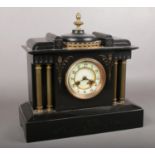 A decorative black slate mantle clock with column supports. Comprises of two holes and enamel dial