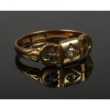 An 18ct gold ring set with a single diamond, flanked by small green coloured stones. Size M. 2.