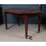 An early 20th century oak and mahogany circular extending dining table with winding handle.