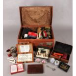 A case of collectables. Including travelling cutlery set, dominoes, unframed sampler,