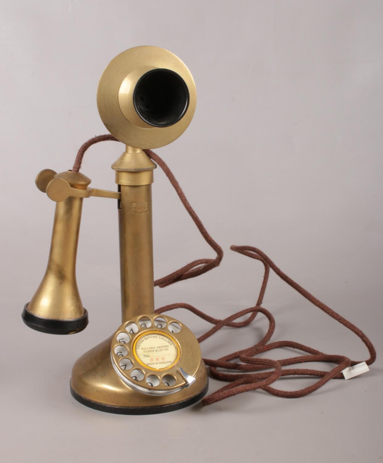 A stick brass telephone. Comprising of a ring dial to the circular base and etched to the front G
