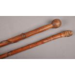 A carved oriental bamboo walking stick along with a similar stick with trailing snake decoration.