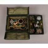 A green leather jewellery box containing an assortment of costume jewellery. To include brooches,
