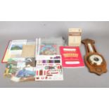 A wooden cased barometer with loreal leaf design together with a folder with postcards, train