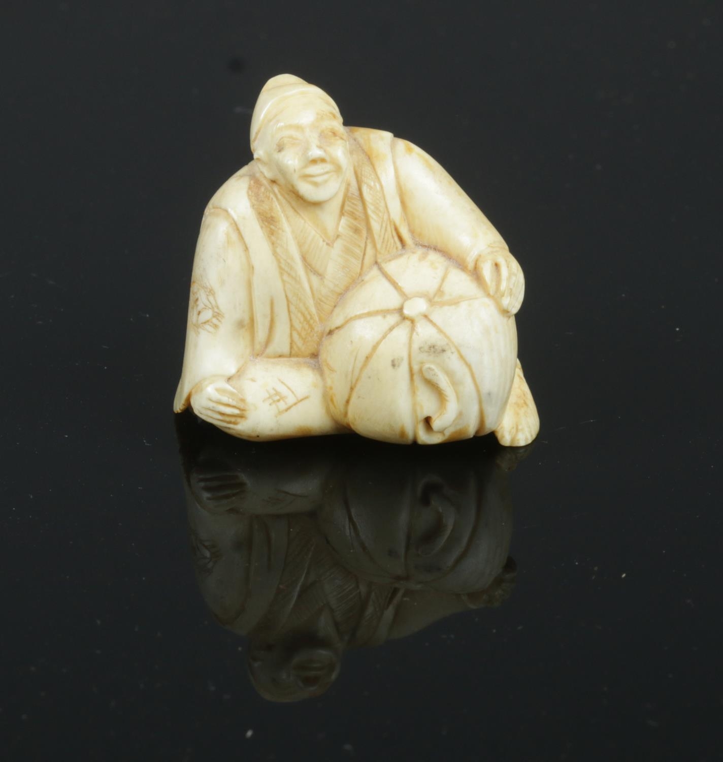 A carved ivory netsuke, in the form of a sitting gentleman.