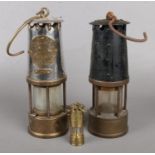 Two vintage miners lamps along with a miniature example.