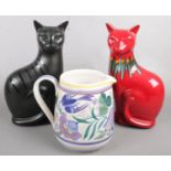 Two Poole pottery cats along with a Poole jug. One cat Lava red ground design.