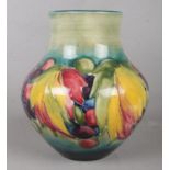 A Moorcroft pottery vase decorated with grapes and leaves on a blue/green ground. Signed to the