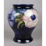 A Moorcroft baluster vase decorated in the Anemone pattern on a deep blue ground. H: 15cm, W: 8cm.