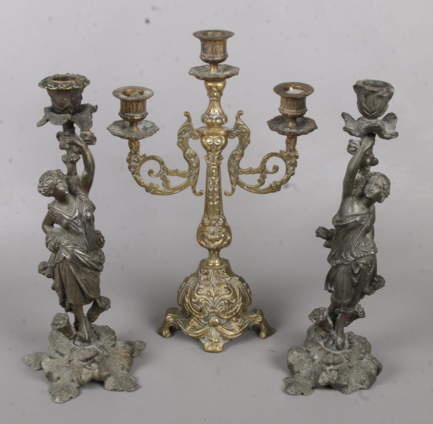 A Pair of Cast Metal Decorative Figural Candlesticks, together with another Brass Example. Some
