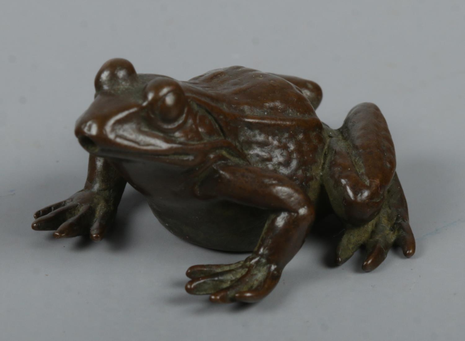 A small Japanese bronze figure of a frog. Marked to base.