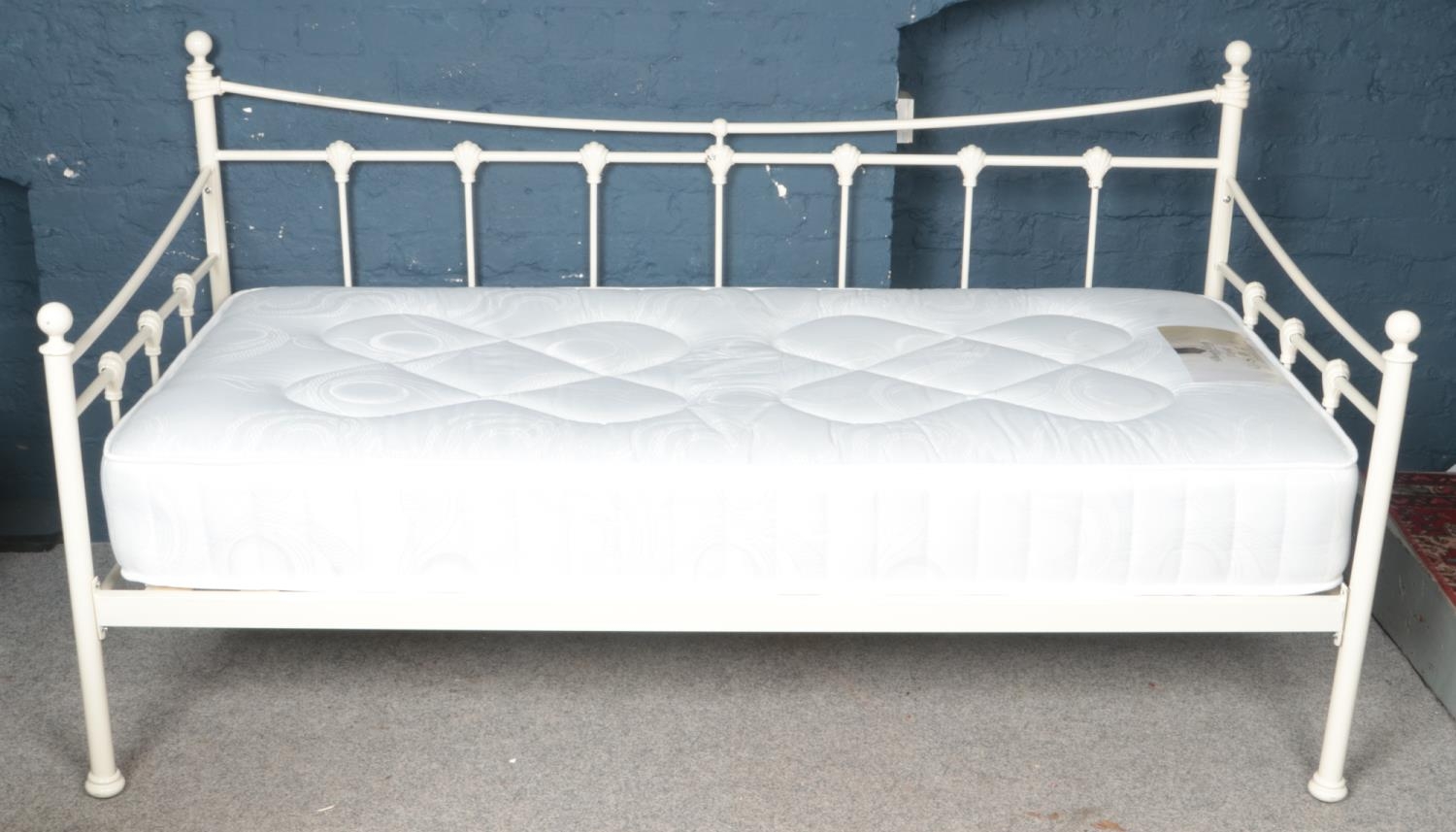 A white painted metal painted day bed with shell mounted decoration.