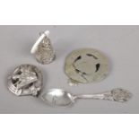 A collection of silver and white metal items. Includes silver spoon, filigree bell, hunting badge