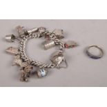 A silver charm bracelet with silver and white metal charms. 71.20g along with a silver ring.