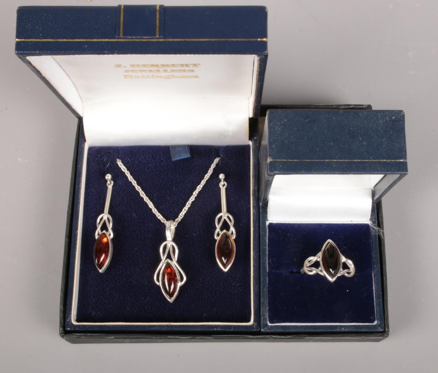 A silver and amber coloured jewellery suite. Includes pendant on chain, earrings and ring.