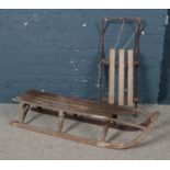 Two vintage sledges. To include a wooden sledge with metal runners and a tubular sledge with