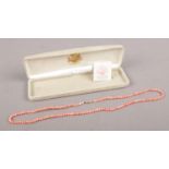 A cased string of Coral beads with 14ct gold clasp.