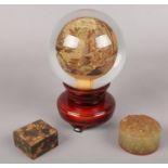An oriental reverse painted glass sphere on wooden stand along with two seal stones. Small chip on