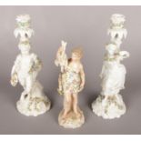 A pair of continental figural candlesticks along with a continental figure of a huntress.