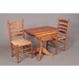 A Pine drop leaf dining table, along with two Pine chairs with rush seat bases.