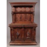 A 19th century carved oak Flemish cupboard. With figural supports, carved door panels and egg and
