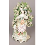 An 18th century Derby porcelain figure modelled as a loot player with bocage surround. 20cm.